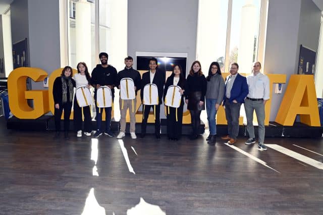_OPM7045 Team Charlie standing in front of Goizueta letters with Goizueta Faculty and UPS Judges
